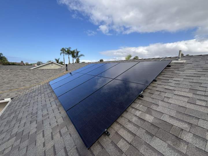 Freshly cleaned black solar panels on a shingle roof
